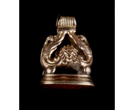 A HARDSTONE SEAL FOB, the cornelian seal with inscribed monogram, to a foliate mount with lion's masks, together with a seed 