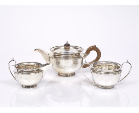 A SILVER THREE PIECE TEA SET, circular teapot with beaded decoration, standing on a turned base, wooden handle and finial, ma