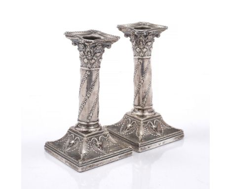 A PAIR OF LATE VICTORIAN SILVER EMBOSSED COLUMN CANDLESTICKS with foliate swag and ram's head decoration, London c.1900 by Wi