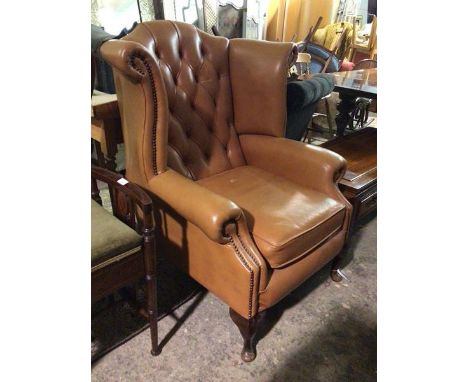 A Georgian inspired wing back armchair in mocha upholstery, with button back, scroll arms and studs to front, on cabriole sup