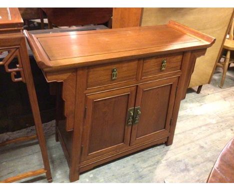 A Chinese side cabinet, the rectangular channelled top with raised sides above two frieze drawers and two cupboard doors, one