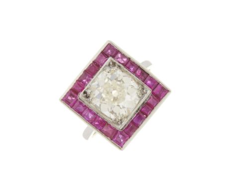 An Art Deco platinum cushion-shape diamond single-stone ring, with calibre-cut ruby surround and openwork gallery, diamond we