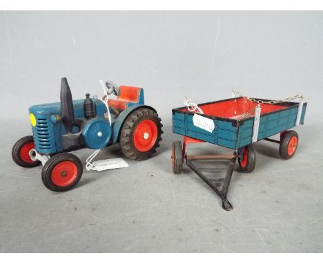 Unmarked Maker - An unboxed and unmarked vintage mechanical tinplate tractor and trailer. The model in blue and red with blac