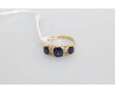 An Edwardian sapphire and diamond ring, the three oval-cut graduated sapphires spaced by two pairs of round brilliant-cut dia