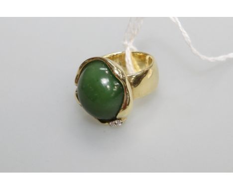 A jade cabochon and diamond ring, the oval cabochon mounted in yellow (unmarked) gold and set with a pair of round brilliant-