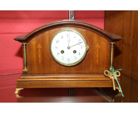 An Edwardian inlaid mahogany mantel clock, the white enamel dial with Arabic numerals, on a moulded base with brass supports,