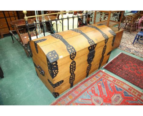 An early 20th Century substantial golden oak iron bound dome topped trunk, with pierced scroll cast strap work. 0.84m by 1.44