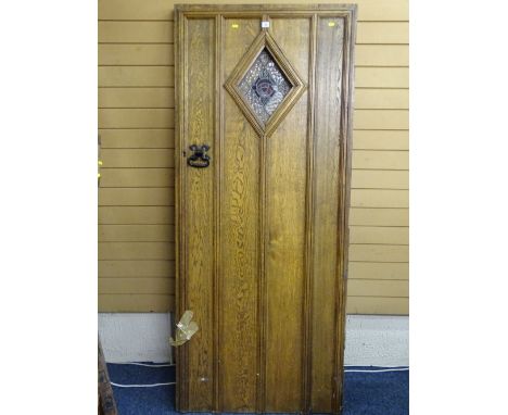 A VINTAGE OAK HEAVY GAUGE HANDLE ENTRANCE DOOR with stained glass diamond shape panel and iron pull, 196cms height, 83.5cms w