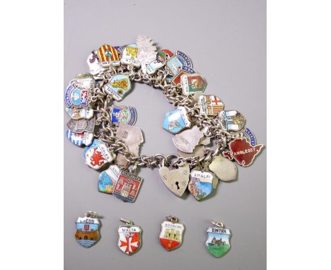 A SILVER CHARM BRACELET with padlock clasp holding in excess of forty mainly silver and enamel place name charms with an addi