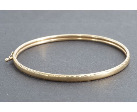 A 9ct gold hinged bangle with "feather" engraved edges, 4.4g
