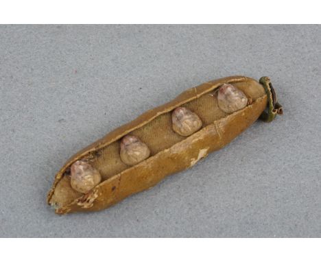 A Victorian novelty / Christmas decoration in the form of a pea pod, containing four porcelain children's heads, in leather, 