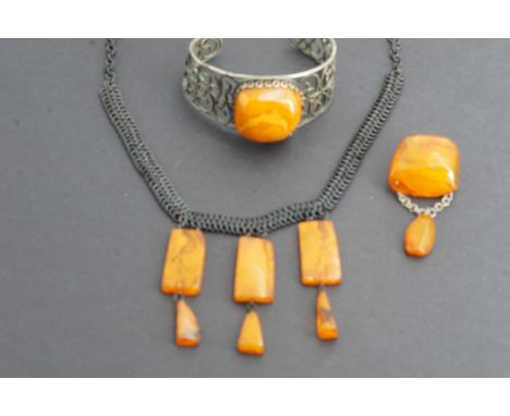 Latvian amber jewellery, including a base metal bangle with large amber nodule, a conforming pendant brooch, and a fringe nec