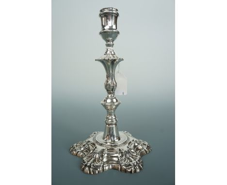 A George III silver candle stick, having an inverted bell form socket, ornately knopped stem, and acanthus moulded sexfoil ba