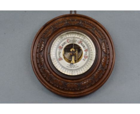 A carved oak barometer by J Dowell and Co, opticians, Maryport and Wigton, 22 cm diameter