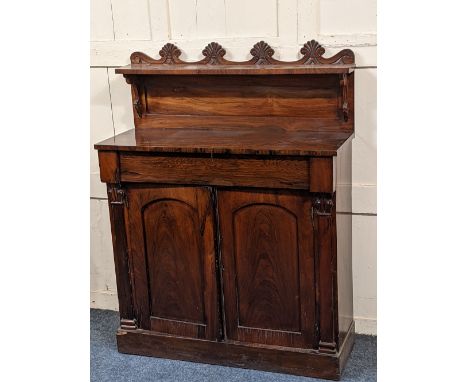 A Regency rosewood chiffonier with raised shelf back and shell carved frieze above single drawer and two panelled cupboards, 