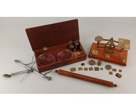 A set of brass postal scales and assorted weights, a set of hand held steel scales with glass pans and a wooden roller ruler