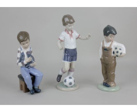 A Lladro porcelain figure of a boy footballer 22cm high, together with two Nao porcelain figures of a boy holding a football 