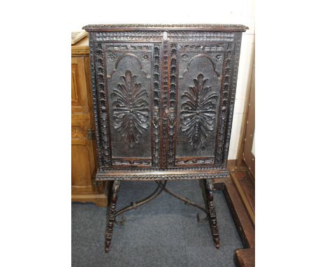 A Continental, possibly Spanish carved oak cabinet with deeply caved panelled sides and doors enclosing interior with arcaded