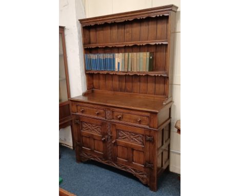 A 20th century oak dresser with three shelf rack on base with two drawers and two carved panel cupboards on bracket feet 123c