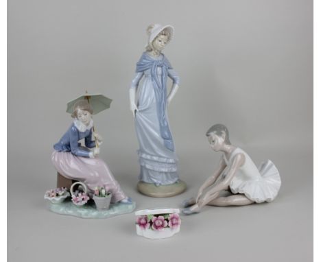 Three Nao porcelain figures comprising a ballerina 14cm high, a lady seated with an umbrella beside flower arrangements appro