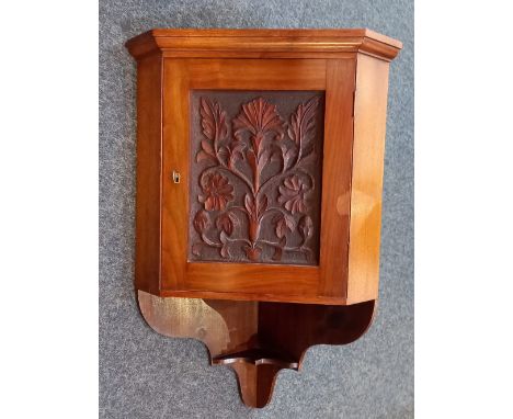 A carved oak hanging corner cupboard with deeply carved floral panel door and shaped support, 42cm