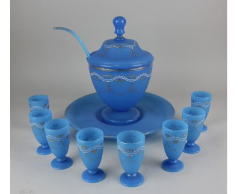 A blue glass punch bowl and cover on stand with matching ladle and eight cups, with gilt and white painted embellishments pun