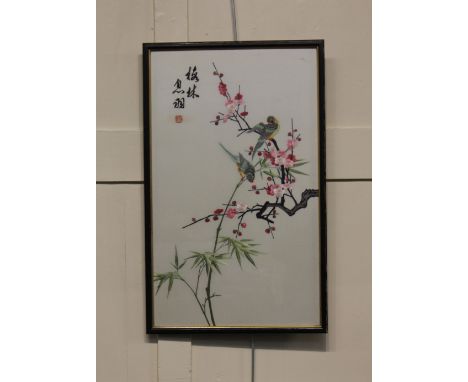 A framed Chinese silk embroidered panel decorated with birds with calligraphy and seal mark as part of the design 57cm by 35c