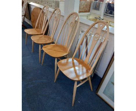 A set of four modern Ercol light wood dining chairs with slatted backs and pieced centres of swans