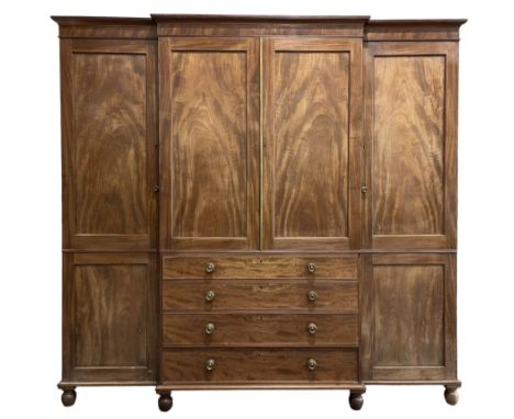 George III mahogany breakfront press wardrobe, the reeded cavetto cornice over banded frieze, the two central figured panel d