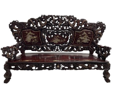 Early 20th century Chinese hardwood settee or hall-bench, the back pierced and heavily carved with dragons and trailing flowe