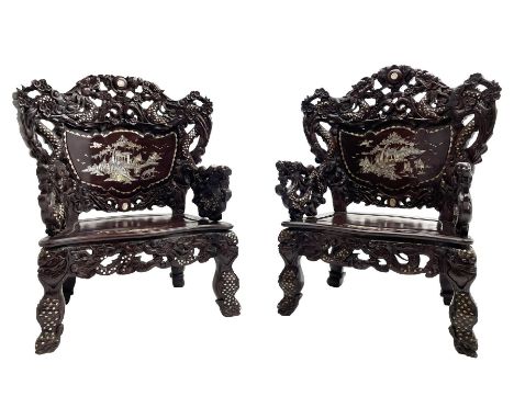 Pair early 20th century Chinese hardwood armchairs, the backs pierced and heavily carved with dragons and trailing flower hea