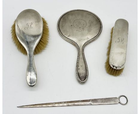 A hallmarked silver mirror along with two similar silver brushes and a silver plated skewer