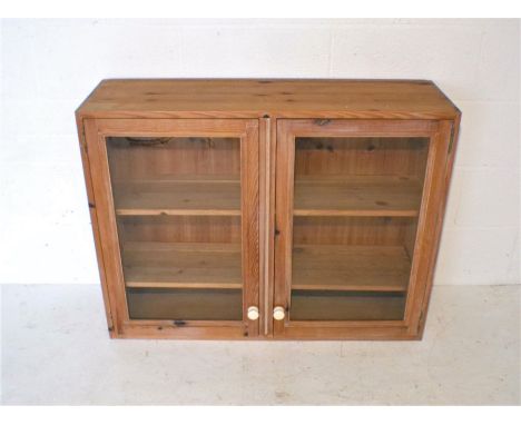 A pine wall hanging glazed display cabinet, with two doors with ceramic handles, length 100cm, height 77cm.