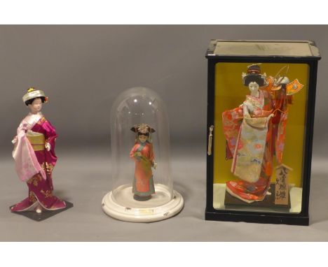 Three Japanese dolls, to include one in a glass dome on enamel stepped circular base, H.27cm (doll), H.41cm (dome), a Japanes