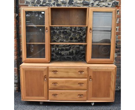 An Ercol Windsor range light elm display cabinet, having three open shelves flanked by two glazed doors, above three drawers 