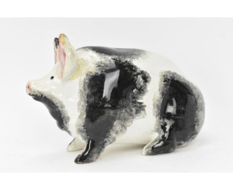 A circa 1900, Wemyss pottery model of a pig, painted with sponge markings and pink ears, seated on its haunches, impressed ma