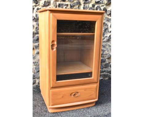 A vintage Ercol Windsor range light elm hi-fi cabinet, having a single bevelled glazed door, fitted with two shelves and a si