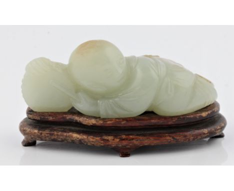 A Chinese pale green Jade boy playing a drum with light brown marks and with a wooden stand, approx 9.5cm x 5cm. BOOK A VIEWI