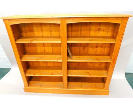 A modern pine open bookcase, with an arrangement of six adjustable shelves, in two sections, on a plinth base, 151cm wide. 