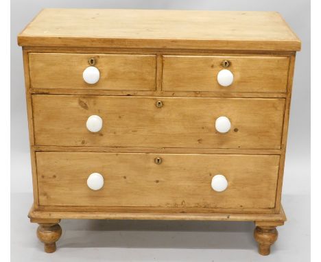 A pine chest of drawers, the top with a plain edge, above two short and two long drawers, each with ceramic handles, on turne