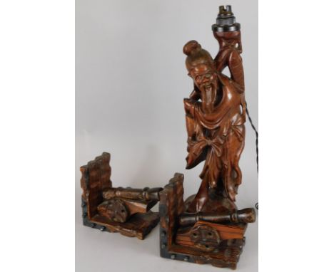 An oriental carved hardwood figure of a fisherman, adapted to a table lamp and a pair of pine cannon mounted bookends