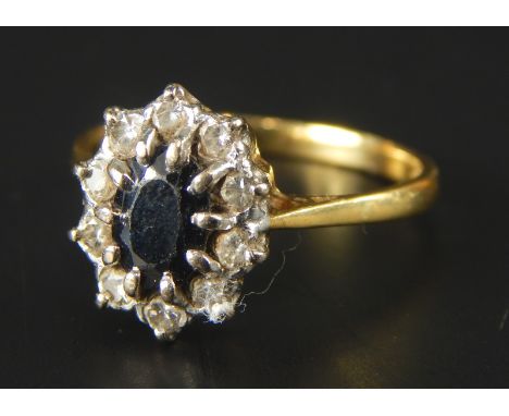 A floral cluster dress ring, with central sapphire, surrounded by ten tiny diamonds, yellow metal, marked 18ct, 3.5g all in. 