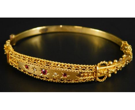 A Victorian 9ct gold bangle, set with garnets and diamonds, with floral scroll work, in a fitted case, 7.9g all in. 
