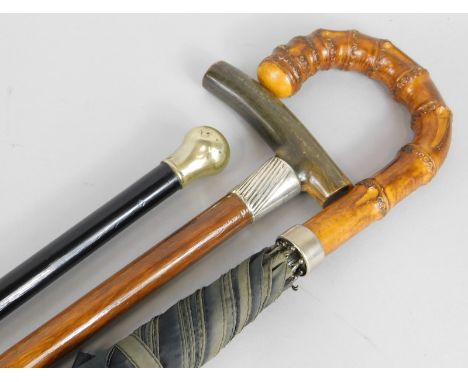 A walking stick, with horn handle and silver collar, a walking cane with white metal handle and an umbrella (3)