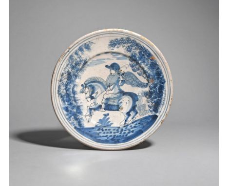 A Spanish maiolica charger  18th century, painted in blue and black with a winged figure on horseback between sponged trees a