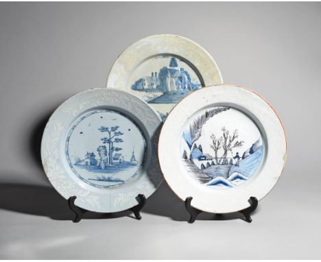Three large Bristol delftware chargers  .1760-70, one painted in blue with a tall pine tree flanked by huts, another with a f
