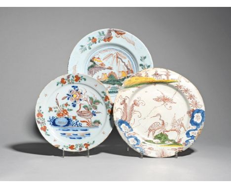 Three delftware plates  c.1760, painted in polychrome enamels, two with cranes amidst flowering branches, the last with low h