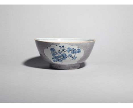 A Bristol delftware punch bowl  c.1755, painted in blue with sprays of flowering plants reserved within shaped panels on a po