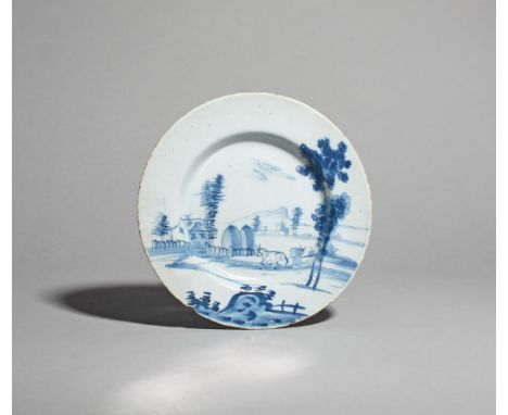 A delftware plate  mid 18th century, probably Bristol, painted in blue with cattle beside two large hayricks behind a low fen