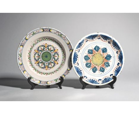 Two delftware chargers  c.1700 and c.1740, one probably London and decorated in blue, yellow and red with a geometric sunburs